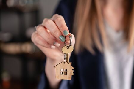 House key in womans hands. Young woman. Modern light lobby interior. Real estate, hypothec, moving home or renting propertyの写真素材