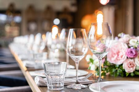 Wine glasses in the foreground. Wedding Banquet or gala dinner. The chairs and table for guests,...