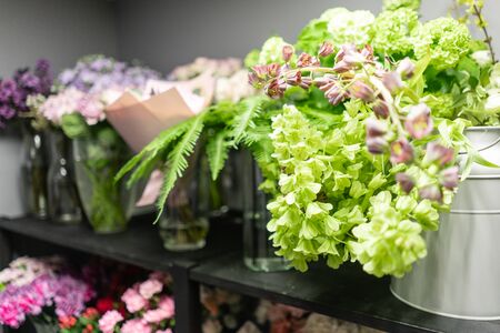 Flower shop concept. Glass vases with different flowers on the shelves of the refrigerator showcases. Abstract background of floral. Flowers composition.の写真素材
