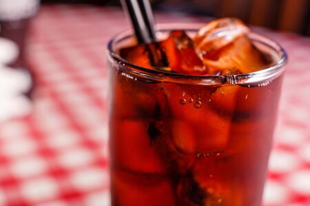 Cold drink beverage. Cola soda with ice and bubble on front view red and white background.の写真素材