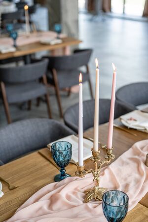 luxury dinner Banquet in the restaurant. Beautiful and exquisite decoration of the wedding celebration. Banquet served table with a beige pink tablecloth, plates and candlesticks with candles.の写真素材