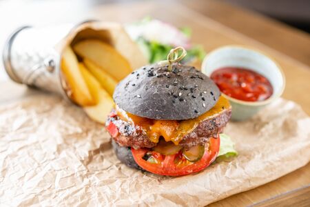 Cheeseburger with lettuce, tomato, fries, and melted cheese. The table in the restaurant. Unhealthy food.の写真素材