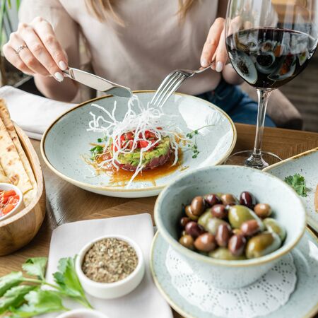 Closeup woman eating tartar in the restaurant. Variety of dishes on the table. Italian cuisineの写真素材