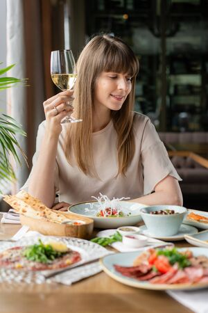 Portrait of a beautiful young elegant woman in the restaurant with a wine glass. Dinner and a...