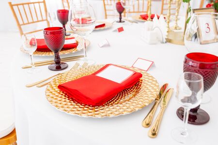 Table setting red napkins and glasses, gold plates. Interior of a wedding tent decoration ready for guests. Decor flowers. Red themeの写真素材