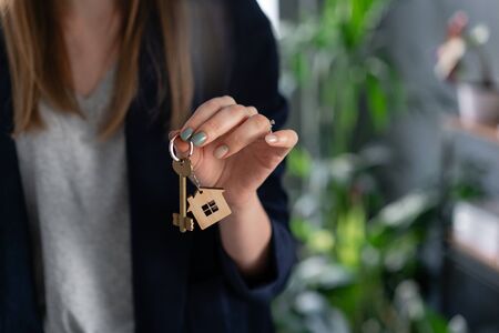 Mortgage concept. Young pretty woman. two house keys in womans hands. . Modern light lobby interior. Real estate, hypothec, moving home or renting property.の写真素材