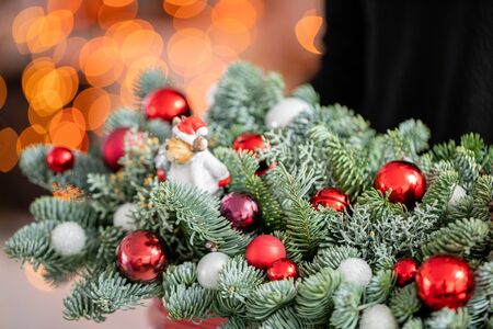Beautiful christmas arrangement of fresh spruce, red balls in a red metal box. Xmas mood. Bokeh of Garland lights on background.の写真素材