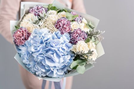 White and blue color. Beautiful bouquet of mixed flowers in woman hands. the work of the florist at a flower shop. Fresh cut flower.の写真素材