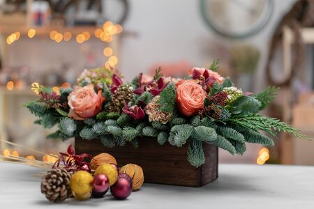 Beautiful festive arrangement of fresh spruce with ball toys in a rustic wooden box. Christmas mood. Bokeh of Garland lights on background.の写真素材