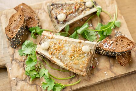 Beef bone marrow with chimichurri sauce and toasted bun. Served on a chopping wooden Board. Menu BBQ...