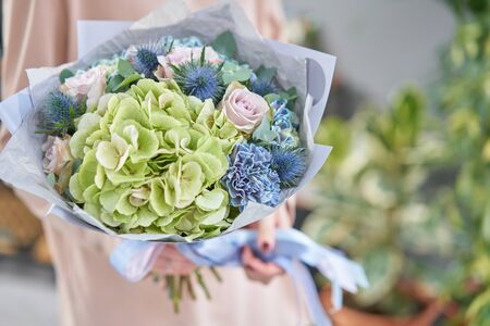 Beautiful bouquets of mixed flowers in womans hands. the work of the florist at a flower shop. Fresh cut flowerの写真素材