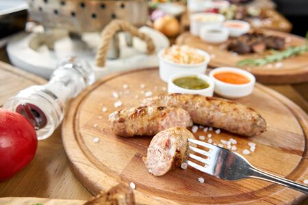 Grilled sausages. Serving on a wooden Board. Barbecue restaurant menu. Many different food on the table. Dinner party or Banquetの写真素材