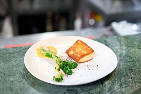 the finished dish in a restaurant kitchen . Salmon steak fillet and garnished with young broccoli. Restaurant menu, a series of photos of different dishesの写真素材