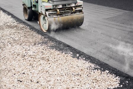 Asphalt Compactors is carrying out road repair work. Laying new asphalt. Large heavy machinery. Construction of a new asphalt road.の写真素材