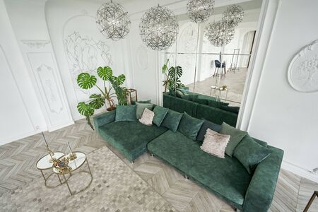 Morning in luxurious light interior in hotel. Bright and clean interior design of a luxury living room with parquet wood floors, fireplace, sofa and houseplant. Stucco on wallsの写真素材