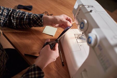Tailor makes bow ties of woolen fabric. Work with sewing machine in a textile studio.