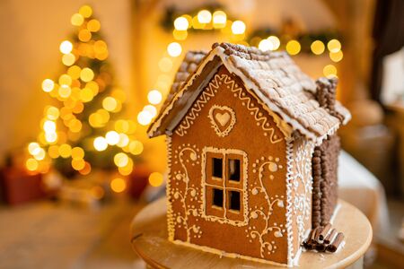 Gingerbread house, concept holiday of Christmas and Happy new year. Defocused lights of Christmas tree. Morning in the bright living room. Holiday mood.の写真素材