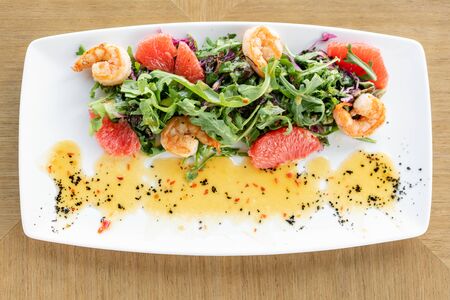 Delicious dish with grilled shrimps, slice grapefruit and arugula salad and spicy fried prawns. Restaurant menu, natural and organic food concept.の写真素材