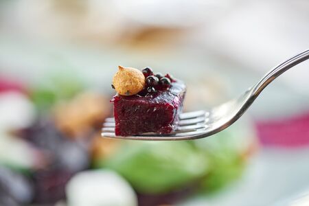 Close-up of a piece of beetroot on a fork. Healthy diet food. Italian salad with beetroot, basil...