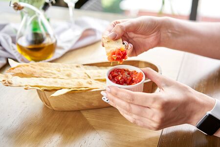 Woman eats Delicious Matzo. Served with tomato and sweet pepper chutney. Matzo, matzah, or matza is unleavened flatbread that is part of Jewish cuisineの写真素材