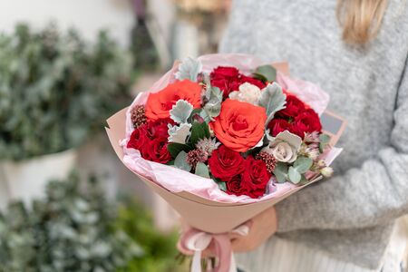 Mixed bouquet of red tones. Beautiful bunch of fresh flowers in womans hands. The work of the florist at a flower shop. Fresh cut flower.の写真素材