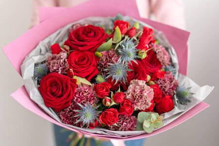 Mixed bouquet of red tones. Beautiful bunch of fresh flowers in womans hands. The work of the florist at a flower shop. Fresh cut flower.の写真素材
