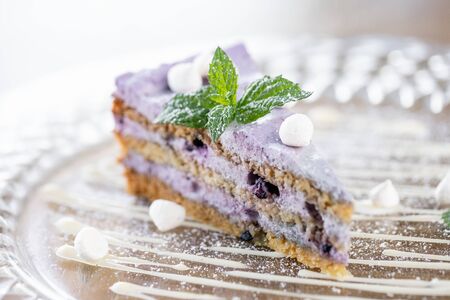 Blueberry sponge cake decorated with meringue and mint leaves. Breakfast in the cafe, morning coffee. on wooden table. Restaurant menuの写真素材