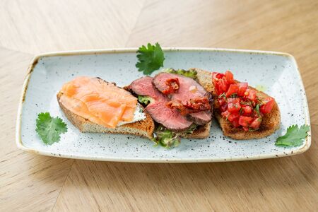 Bruschetta with beef, tomatoes and salmon. Various snacks and antipasti on the table. Restaurant menu. Italian cuisineの写真素材