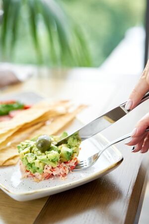 Woman eats salad crab, avocado, citrus oil, spices. Crab meat with matzo on white plate for cooked seafood.の写真素材