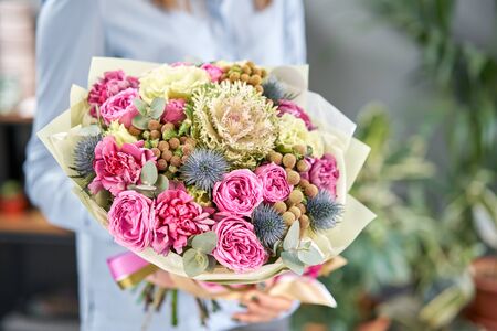 European floral shop. Beautiful bouquet of mixed flowers in womans hands. the work of the florist at a flower shop. Delivery fresh cut flower.の写真素材