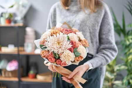 European floral shop. Beautiful bouquet of mixed flowers in womans hands. the work of the florist at a flower shop. Delivery fresh cut flower.の写真素材