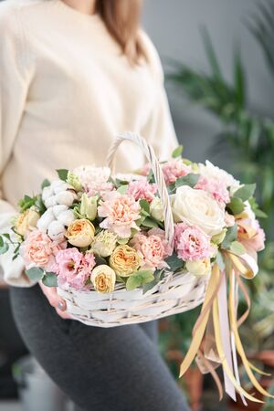 Flower arrangement in Wicker basket. Beautiful bouquet of mixed flowers in woman hand. Floral shop concept . Handsome fresh bouquet. Flowers deliveryの写真素材