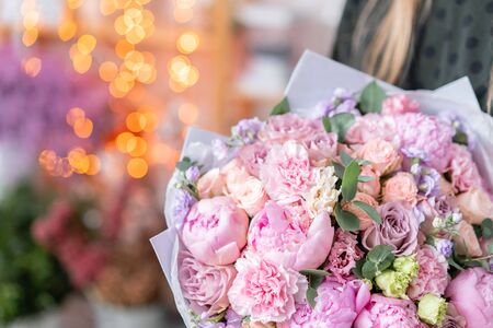 Pink peonies, Sarah Bernhardt and different flowers. European floral shop. Beautiful bouquet in womans hands. the work of the florist at a flower shop. Delivery fresh cut flower.の写真素材