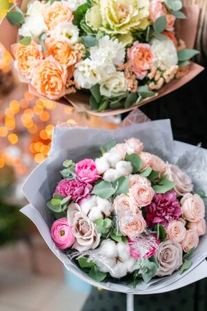 European floral shop. Two Beautiful bouquets of mixed flowers in womans hands. the work of the florist at a flower shop. Delivery fresh cut flower.の写真素材
