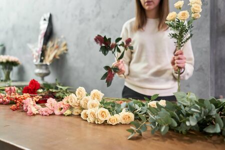Step by step florist woman creates red beautiful bouquet of mixed flowers. Handsome fresh bunch. Education, master class and floristry courses. Flowers delivery. European floral shop conceptの写真素材