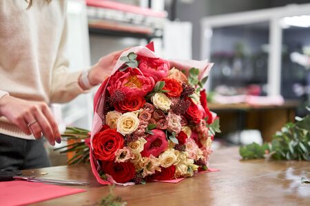 Step by step florist woman creates red beautiful bouquet of mixed flowers. Handsome fresh bunch....