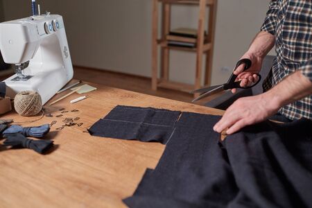 Closeup Tailor cutting wool fabric. the line pattern. Craftsman Makes rectangular blanks for Bow ties of woolen fabric. Work with sewing machine in a textile studio.の写真素材