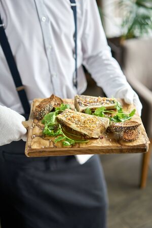 The waiter is holding a plate Beef bone marrow with chimichurri sauce and toasted bun. Served on a chopping wooden Board. Menu BBQ restaurantの写真素材