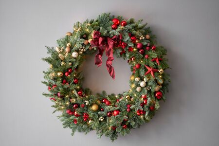 Beautiful festive wreath of fresh spruce on Gray wall. Xmas circlet with red and gold ornaments and balls. Christmas mood.の写真素材