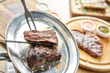 The waiter is butchering griled meat with a knife. Grilled fillet steaks with Pickled cabbage and...