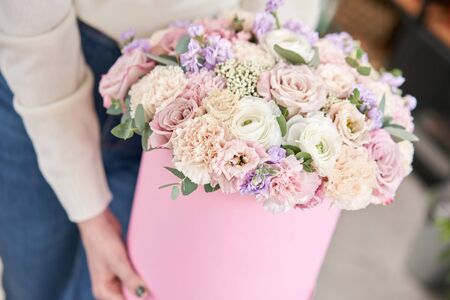 European floral shop. Floral bunch in round box. Bouquet of beautiful Mixed flowers in woman hand. Excellent garden flowers in the arrangement , the work of a professional florist.の写真素材
