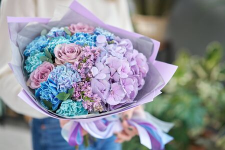 European floral shop. Beautiful bouquet of mixed flowers in womans hands. the work of the florist at a flower shop. Delivery fresh cut flower.の写真素材