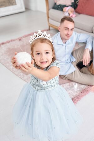 Loving family Mom and dad, little daughter . Parents and baby child having fun near Christmas tree and white fireplace indoors. Merry Christmas and Happy New Year. Cheerful pretty people.の写真素材