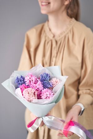 Young happy woman holding a beautiful bunch of colorful hyacinths in her hands. Present for a smiles girl. Flowers bouquet.の写真素材