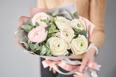 Persian buttercup in womans hands. Bunch pale pink ranunculus flowers with green eucalyptus. The work of the florist at a flower shopの写真素材