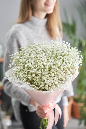White gypsophila. Beautiful bouquet of mixed flowers in womans hands. the work of the florist at a flower shop. Fresh cut flower.の写真素材