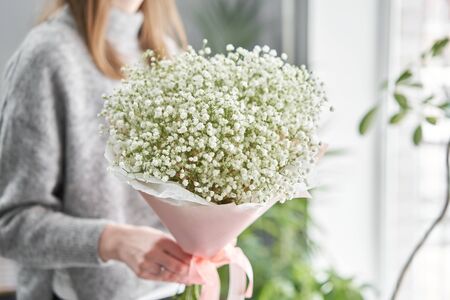White gypsophila. Beautiful bouquet of mixed flowers in womans hands. the work of the florist at a flower shop. Fresh cut flowerの写真素材