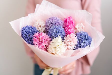 Young happy woman holding a beautiful bunch of colorful hyacinths in her hands. Present for a smiles girl. Flowers bouquetの写真素材
