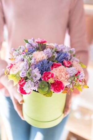 European floral shop. Floral bunch in round box. Bouquet of beautiful Mixed flowers in woman hand. Excellent garden flowers in the arrangement , the work of a professional florist.の写真素材