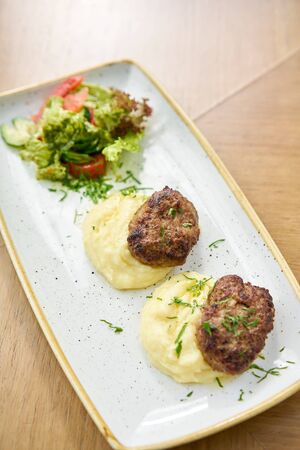 Delicious juicy meat cutlets, mashed potatoes sprinkled with greens and fresh healthy salad of tomatoes and lettuce leaves.の写真素材